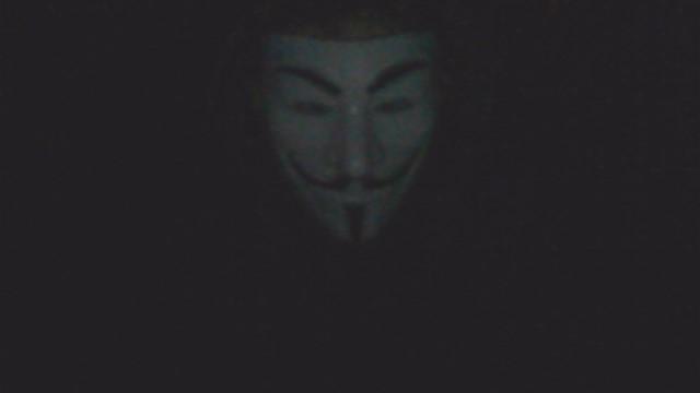 Ein unscharfes Bild einer Guy-Fawkes-Maske vor einem dunklen Hintergrund.