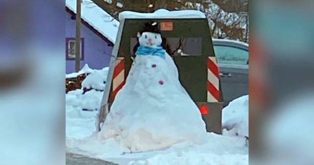 Ein Schneemann mit schwarzem Hut und blauem Schal steht direkt vor einem Blitzer und verdeckt diesen.