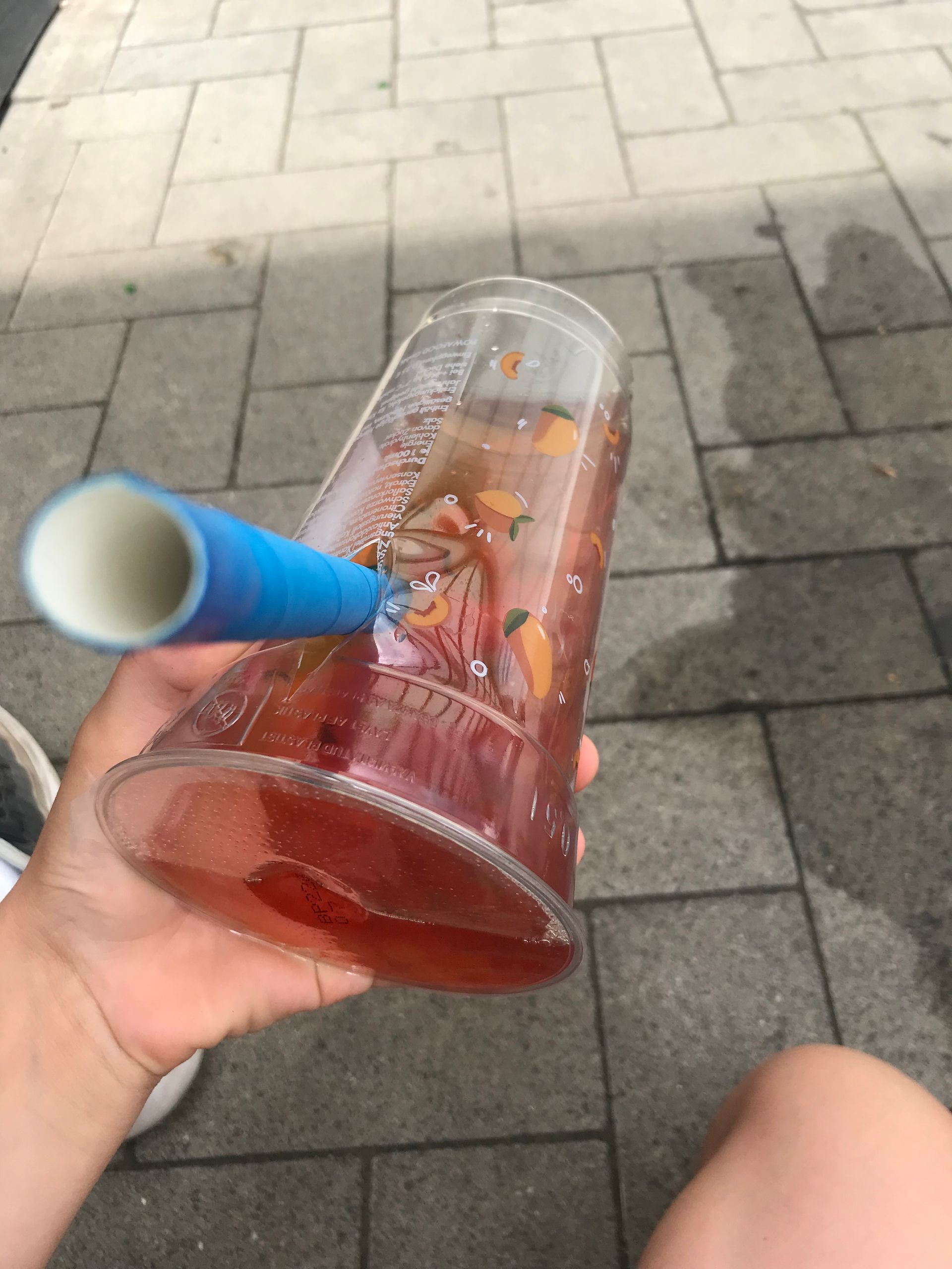 Ein Becher Bubbletea mit einem breiten blauen Strohhalm aus Kunststoff.