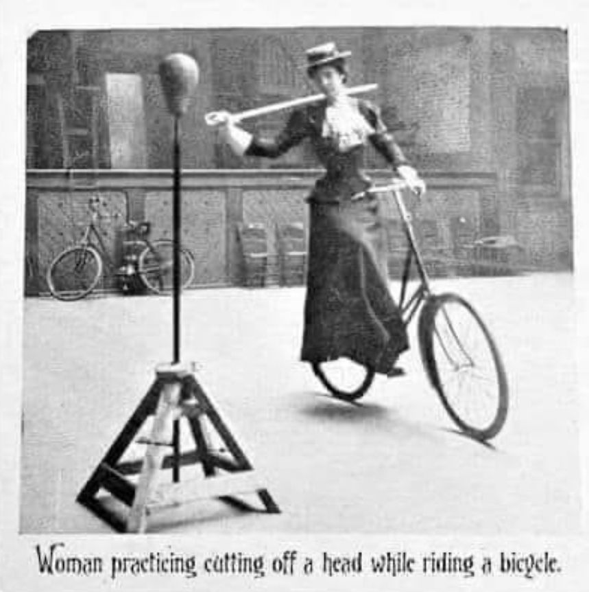 Woman practicing cutting off a head while riding a bicycle.