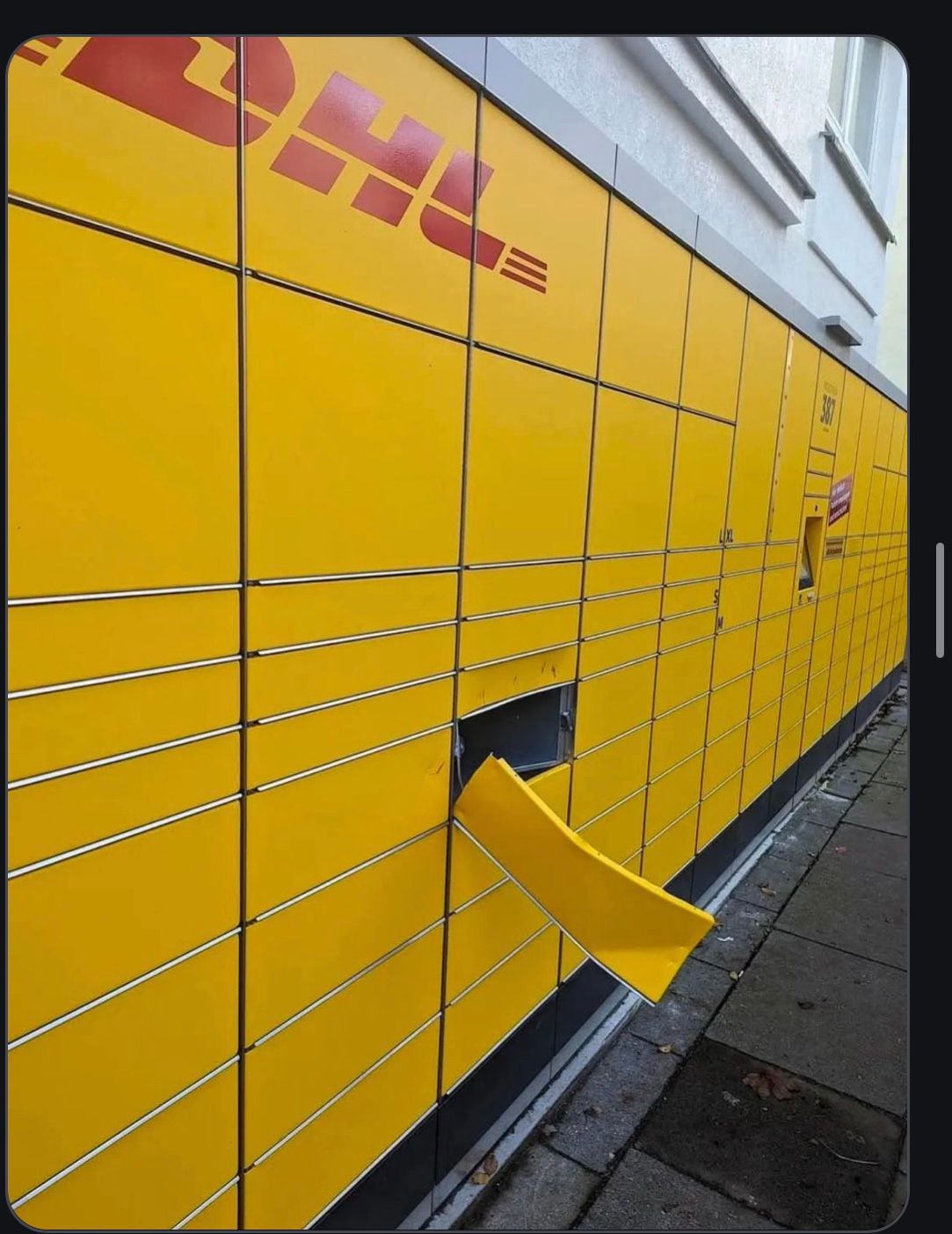 Ein gelber DHL-Paketautomat, dessen untere Klappe abgebrochen ist. Der Text lautet: "Wenn ich einmal in dem blöden Ding war, jetzt ist er kaputt."