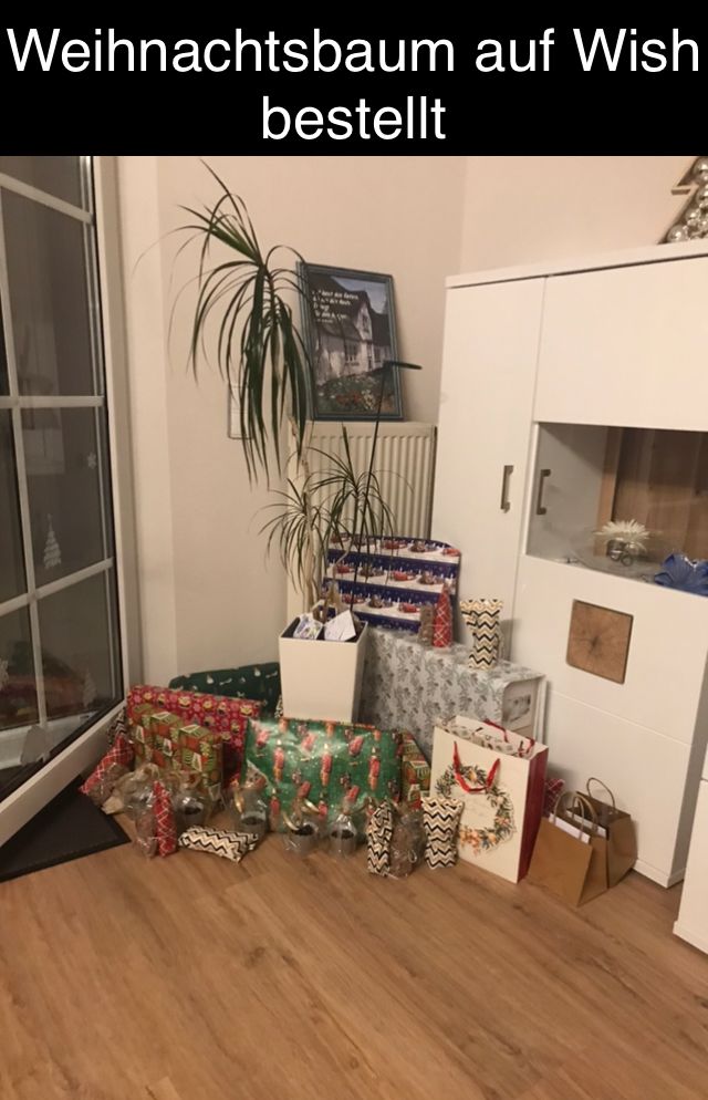 Ein Foto zeigt eine Ecke eines Wohnzimmers. Viele Weihnachtsgeschenke liegen auf dem Boden. Im Hintergrund ist ein grüner Baum zu sehen. Der Text im Bild lautet: "Weihnachtsbaum auf Wish bestellt".