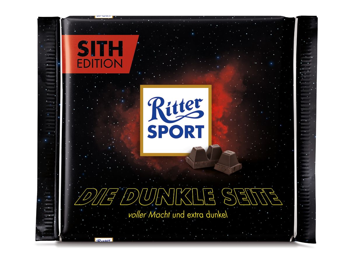 Eine Ritter Sport Schokolade in einer "Sith Edition" Verpackung. Die Verpackung ist schwarz mit einem Sternenhintergrund. Die Aufschrift lautet "Sith Edition", "Ritter Sport", und "Die dunkle Seite", sowie "voller Macht und extra dunkel". Es sind auch kleine Schokoladenstücke abgebildet.